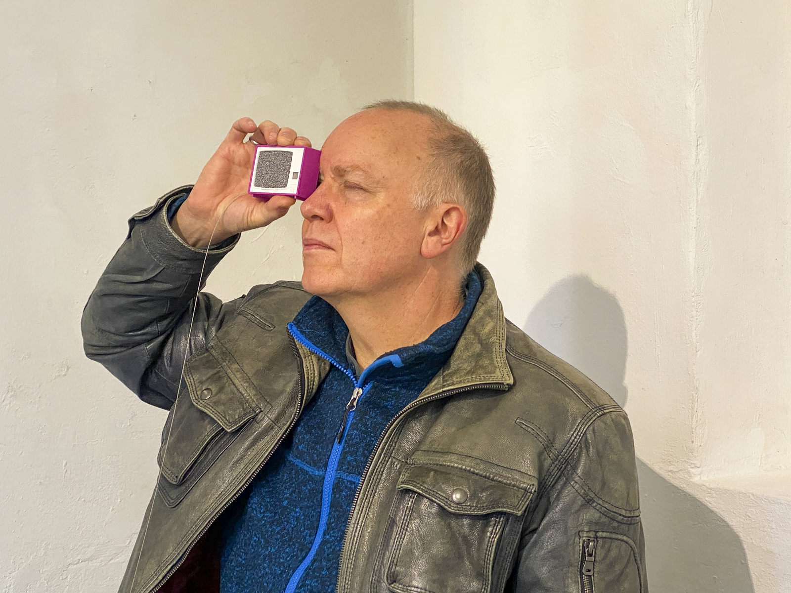 Farbbild (born-digital): Ein Mann blickt durch ein Plastiskop in der Ausstellung en miniature der schaelpic photokunstbar, Köln. (Foto: © Tobias D. Kern, 11/2025)